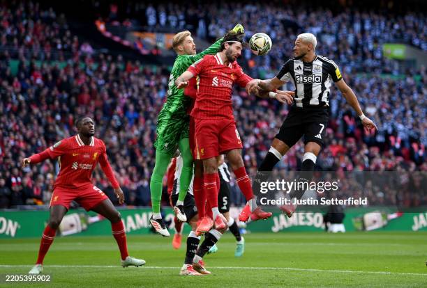 Dominik Szoboszlai of Liverpool and Joelinton of Newcastle United compete for a header as Caoimhin Kelleher of Liverpool attempts to punch the ball...