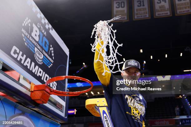 Head coach Dusty May of the Michigan Wolverines celebrates after cutting the nets after defeating the Wisconsin Badgers in the Big Ten men's...