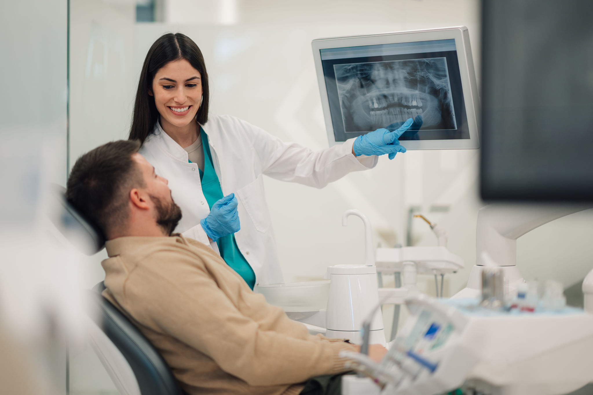 Dentist showing teeth x-ray to patient in modern clinic Dentist showing teeth x-ray to patient in modern clinic