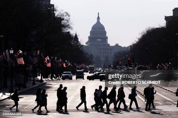 Commuters cross Pennsylvania Avenue in downtown Washington, DC, as they head towards the Ronald Reagan Building and International Trade Center, which...