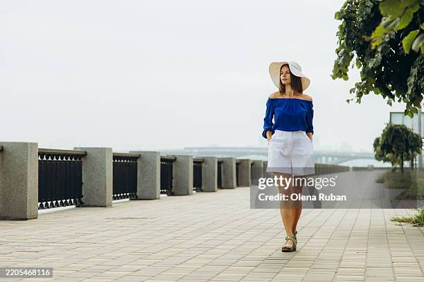 young pretty woman in a blue blouse and a white shorts walking on a promenade in a summer day. - dnieper river stock pictures, royalty-free photos & images