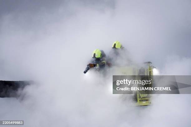 Firefighters douses flames of a fire that broke out at a substation supplying power to Heathrow Airport in Hayes, west London on March 21, 2025....