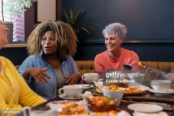 women sharing pizza and stories during relaxed gathering - close to stock pictures, royalty-free photos & images