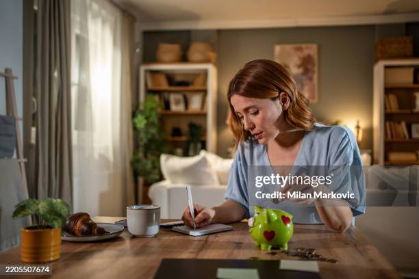 woman managing home finances and savings with piggy bank - savings stock pictures, royalty-free photos & images