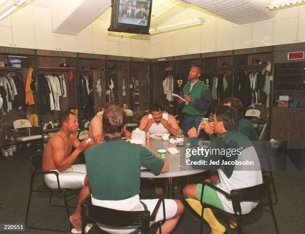 Members of the Oakland Athletics eat and watch tv in the clubhouse after the final major league baseball game before the impeniding players strike.