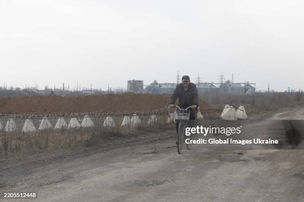 Man rides a bicycle along the road against the backdrop of a damaged city on March 16, 2025 in Pokrovsk, Donetsk Oblast, Ukraine. Residents of...