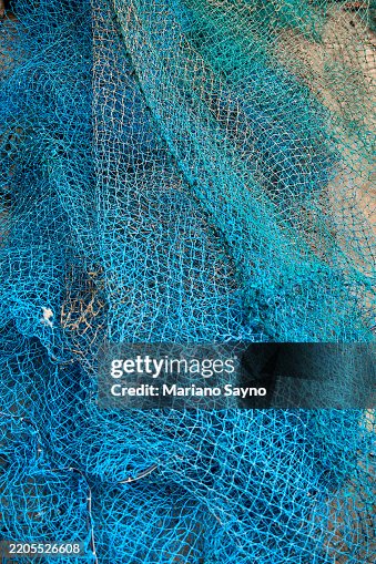 A worn-out blue nylon fishing net. A worn-out blue nylon fishing net.