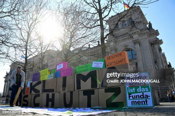 An activist sets up boxes with the lettering 'Climate protection' in front of the Reichstag building housing the Bundestag, in Berlin on March 21...