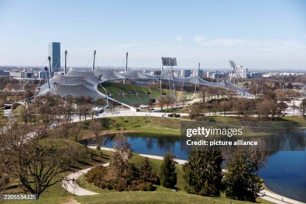 March 2025, Bavaria, Munich: The Olympic grounds in the Olympic Park with the Olympic Stadium in Munich . The O2 Tower can be seen in the background....