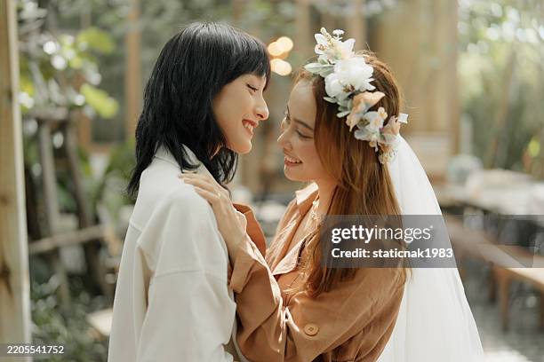adorable lgbtq couple smile and take photos together in a surprise marriage proposal. - beach wedding stock pictures, royalty-free photos & images