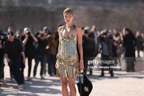 Guest seen wearing Casablanca gold dazzling metallic dress, gold bold statement necklace, Casablanca black handbag with a gold handle, before...
