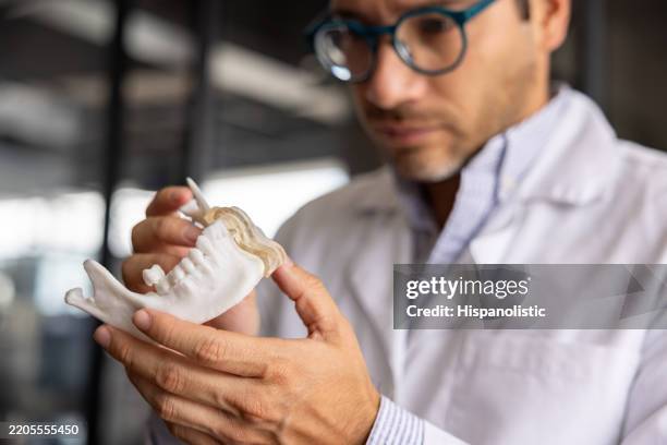 3d designer looking at a dental mold at a laboratory - implante imagens e fotografias de stock