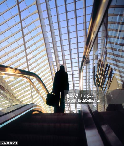commuter on top of a moving escalator at modern train station - blickwinkel der aufnahme stock-fotos und bilder