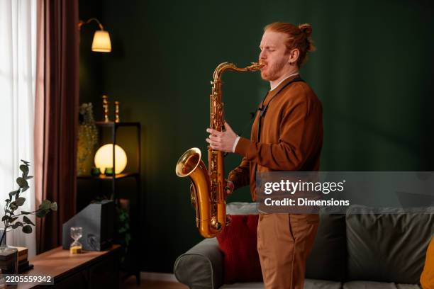 jeune musicien jouant du saxophone à la maison - saxophone photos et images de collection