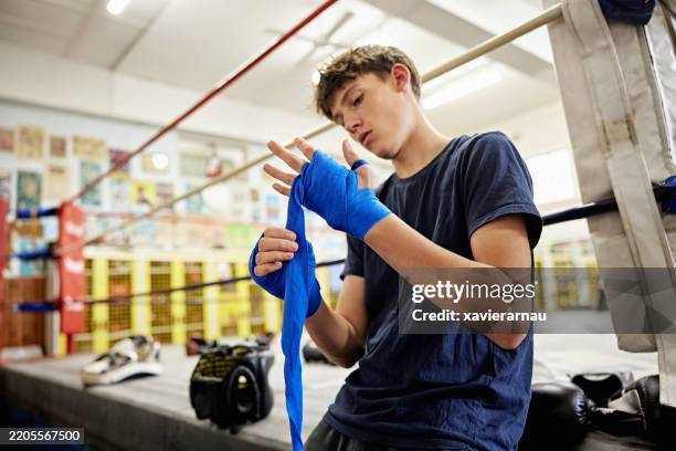 teenage boy wrapping his hands at youth boxing club - youth club stock pictures, royalty-free photos & images