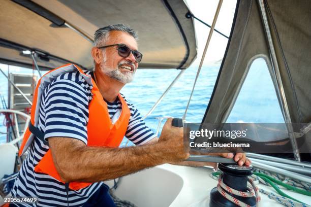 mature man on the sailing boat using a winch - sailor man stock pictures, royalty-free photos & images