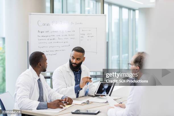 diverse doctors discussing case study using laptop and x-ray - neurosurgeon stock pictures, royalty-free photos & images