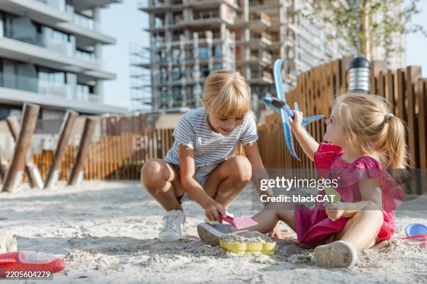 two children playing with sand in an urban playground near residential buildings - sandlåda bildbanksfoton och bilder