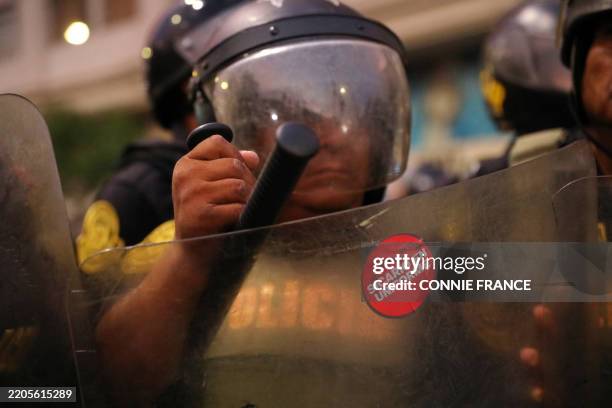 Sticker reading "Sicario in Uniform" is seen on the shield of a riot police officer during a national march against organized crime and hired...