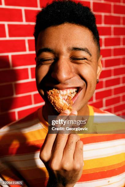young man enjoying crispy chicken - eating chicken wing stock pictures, royalty-free photos & images