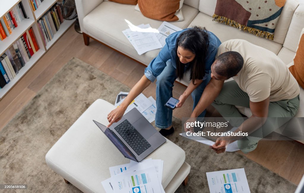 Couple at home paying bills online using technology