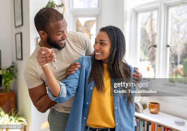 couple looking very happy holding the keys of their new house - huiseigenaar stockfoto's en -beelden