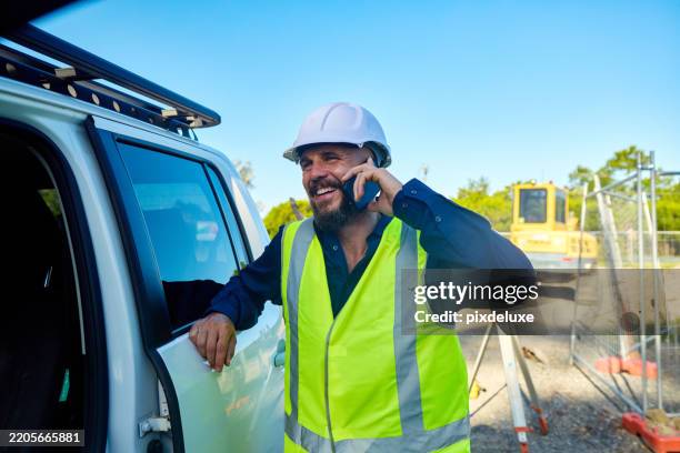 smiling engineer talking on mobile phone at construction site in australia - waistcoat stock pictures, royalty-free photos & images