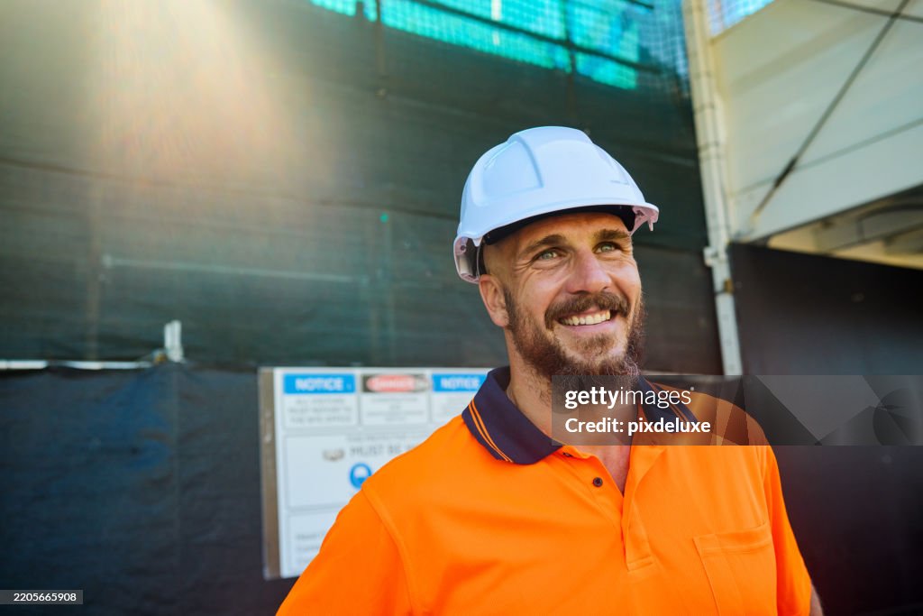 Smiling engineer wearing hardhat at construction site in australia