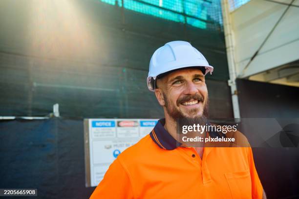 smiling engineer wearing hardhat at construction site in australia - construction-worker stockfoto's en -beelden