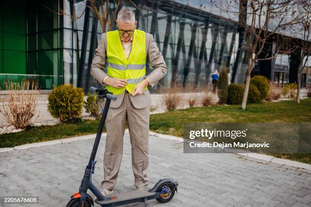 persona de negocios que va a trabajar con scooter de empuje eléctrico y tiene un chaleco reflectante de seguridad en la parte superior - material reflector de seguridad fotografías e imágenes de stock
