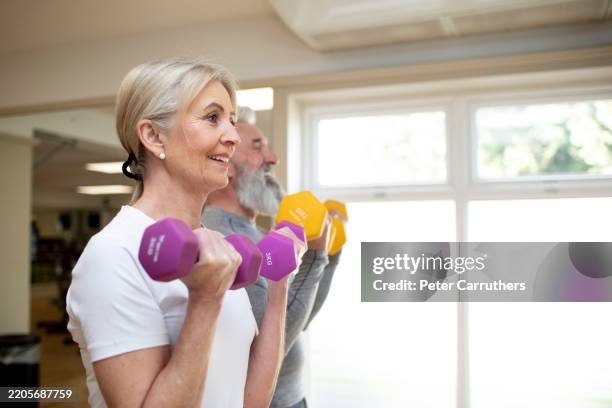 mature woman with her partner exercising with dumbbells - hand weight stock pictures, royalty-free photos & images