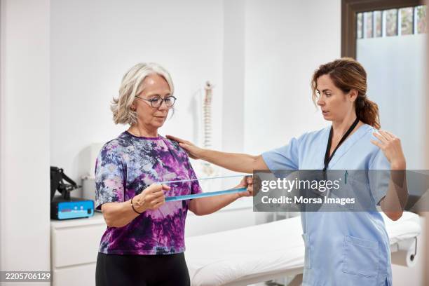 physical therapist helping woman doing exercise - rehabilitation center stock pictures, royalty-free photos & images