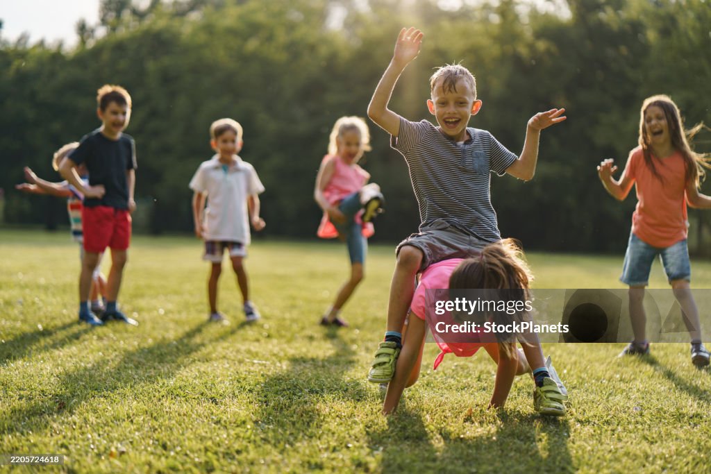 Children playing leapfrog game in public park