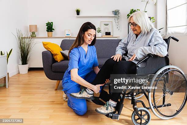 female nurse assisting elderly woman in wheelchair at home - house call stock pictures, royalty-free photos & images