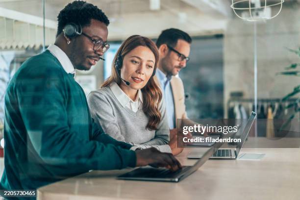 colleagues working in a call centre - oficio de comunicaciones fotografías e imágenes de stock