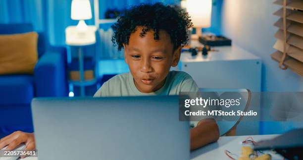 young african-american boy learning programming codes on laptop, engaged in stem learning project involving robotics in home at night. stem education robotics courses online. - game programming stock pictures, royalty-free photos & images
