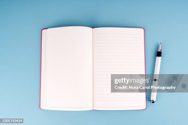 blank notepad and pen on blue background - blank pages in open book overhead view stock pictures, royalty-free photos & images