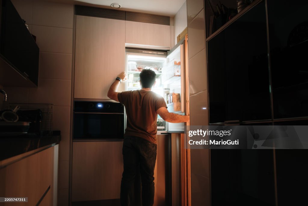 Mann, der nachts einen Kühlschrank öffnet
