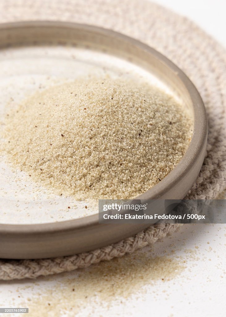 Raw uncooked fonio seeds on a plate on white table,Top view African ancient pseudocereal