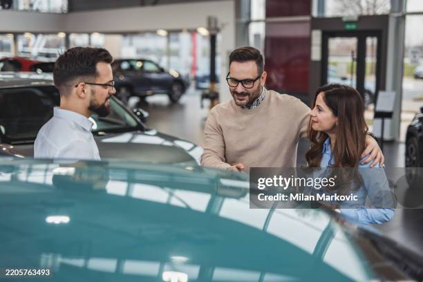paar wählt ein neues auto im autohaus mit autoverkäufer - autokredit stock-fotos und bilder