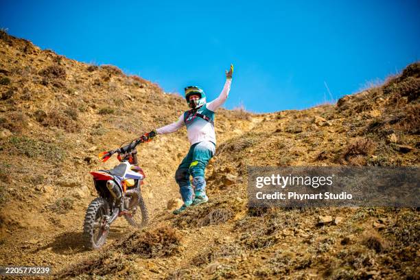photo sportive d’un motard qui est un pilote professionnel en enduro et motocross en plein air. vélo tout-terrain et homme faisant des cascades dans la nature. forêt et sable, personne utilisant des équipements sportifs. - motocross photos et images de collection