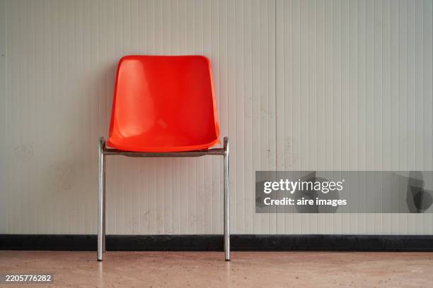 lonely orange plastic chair standing in an empty waiting room - chair stock pictures, royalty-free photos & images