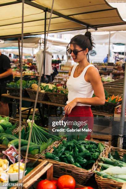 woman shopping for fresh vegetables at an outdoor market - ervaringsvakantie stockfoto's en -beelden