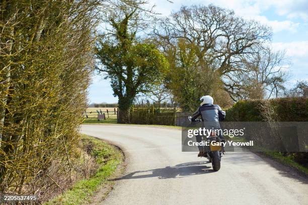 middle aged man enjoying riding his motorbike in the countryside - motorbike stock pictures, royalty-free photos & images
