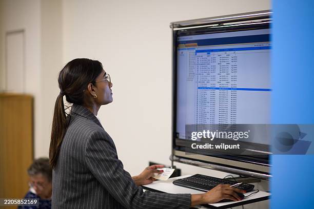 professional indian female doctor reviewing digital records on a monitor in an office setting - operating procedures standardization stock pictures, royalty-free photos & images
