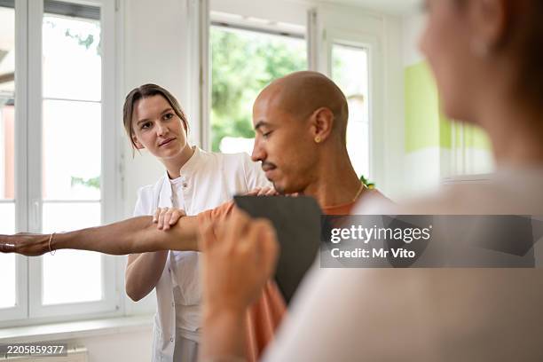 a patient with a sports injury undergoing examination and therapy by a physiotherapist. - sportmedizin stock-fotos und bilder