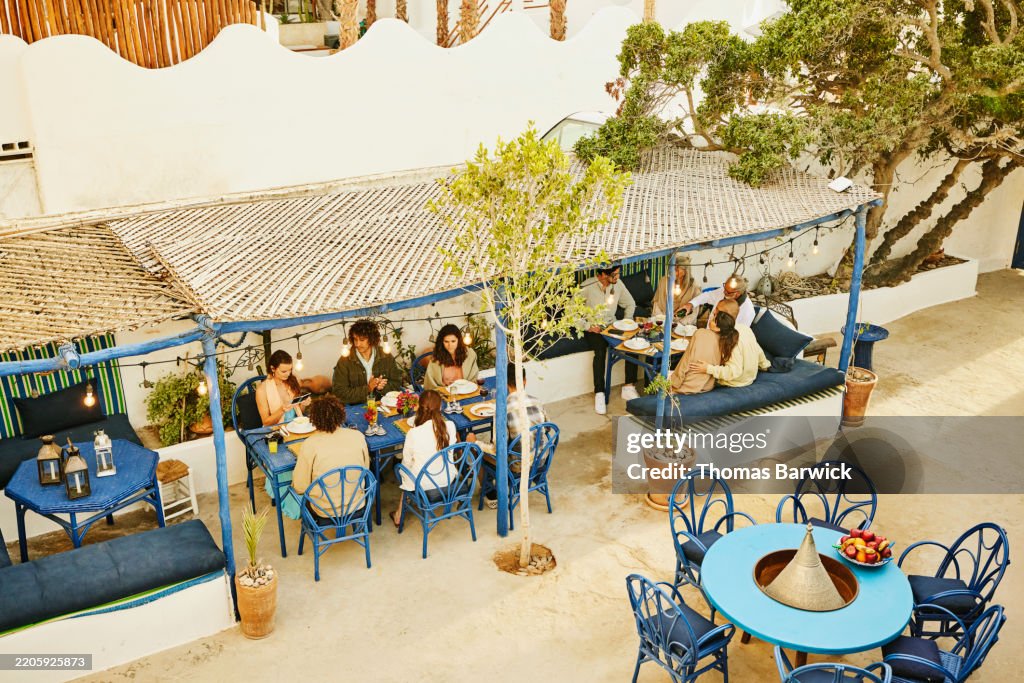 Extreme wide shot friends enjoying dinner party at outdoor restaurant