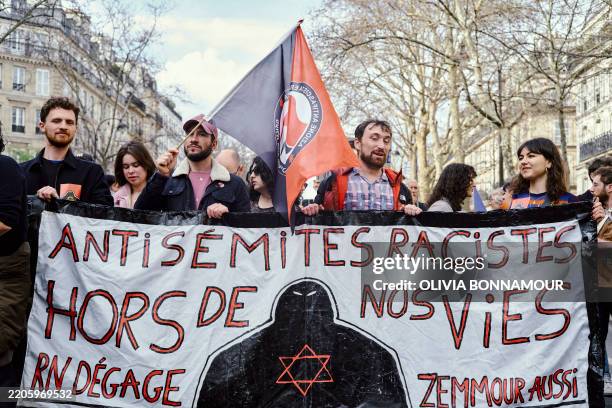 Demonstrators hold a large banner during a protest in Paris, on March 22, 2025.
