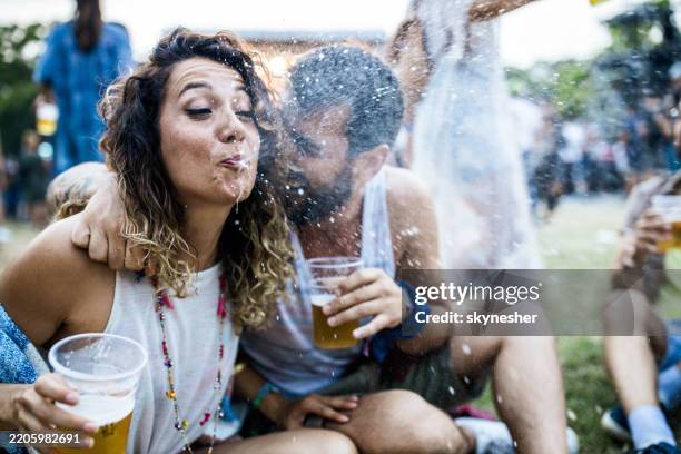 young woman having fun while spitting beer on a music concert. - spitting stock pictures, royalty-free photos & images
