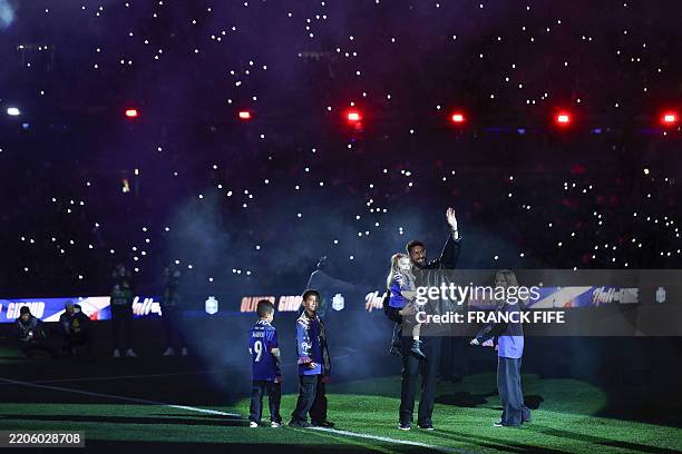 Former France International forward Olivier Giroud waves to the crowd as he walks on the pitch with his children during a tribute to him ahead of the...